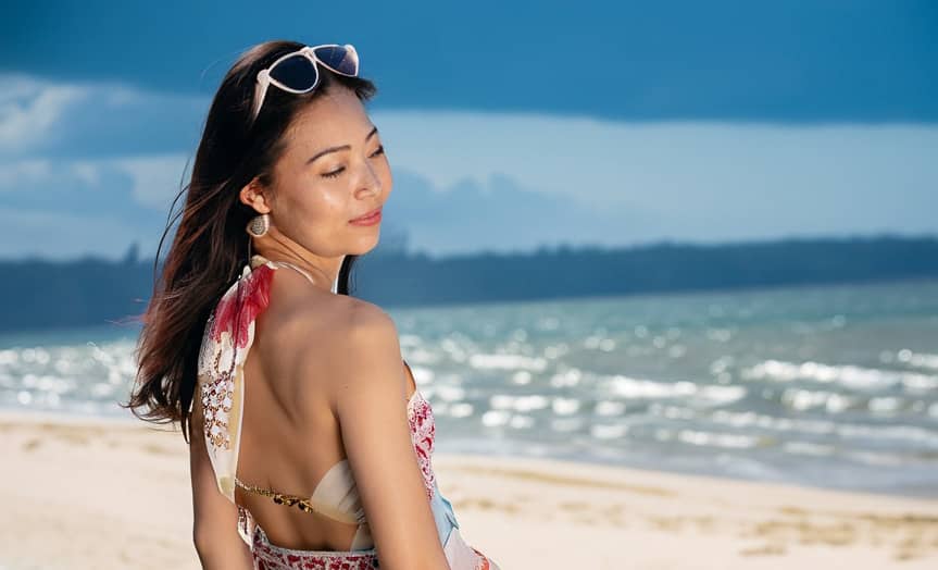 Une femme portant une robe et des lunettes de soleil sur la plage.